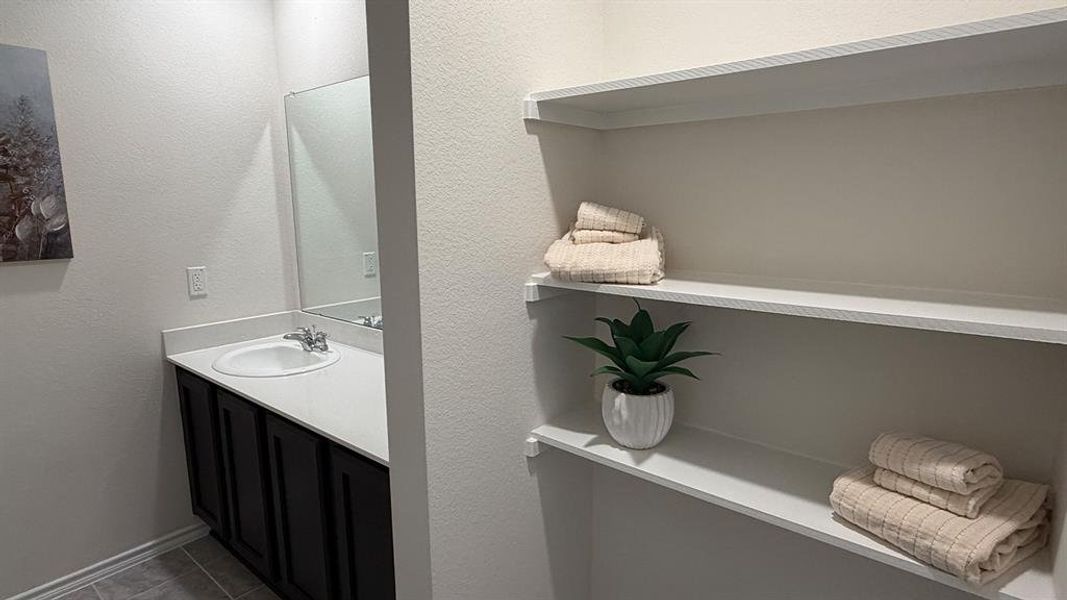Bathroom with vanity, a textured wall, and tile patterned flooring