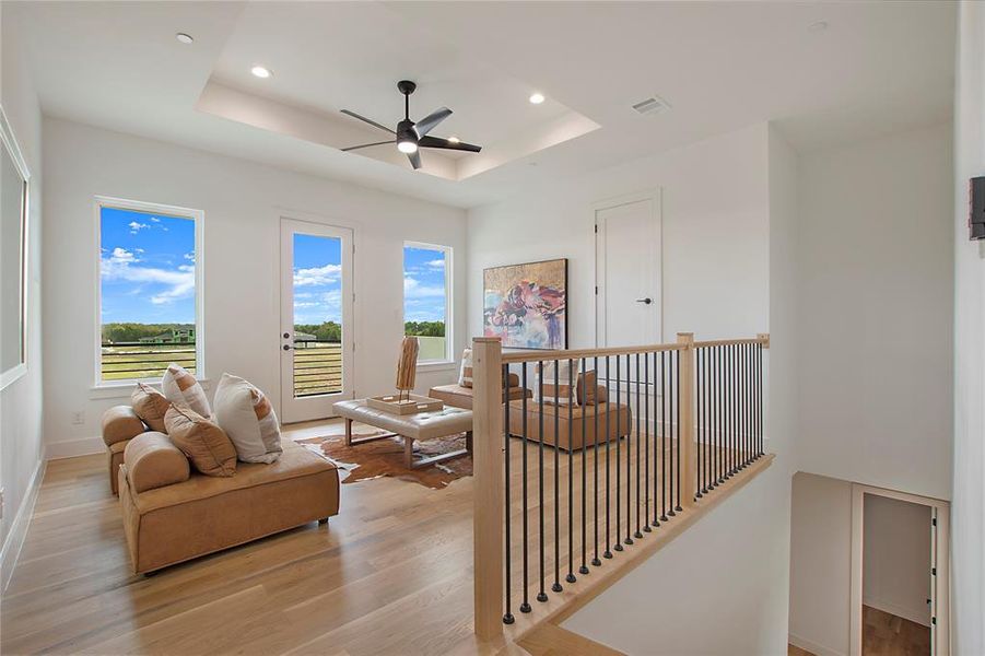 Sitting room featuring a tray ceiling, light wood-type flooring, and ceiling fan