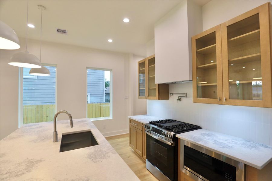 The balanced combination of sleek glass-front and warm wood-style cabinets adds both elegance and warmth to this gourmet kitchen. The balanced combination of sleek glass-front and warm wood-style cabinets adds both elegance and warmth to this gourmet kitchen.