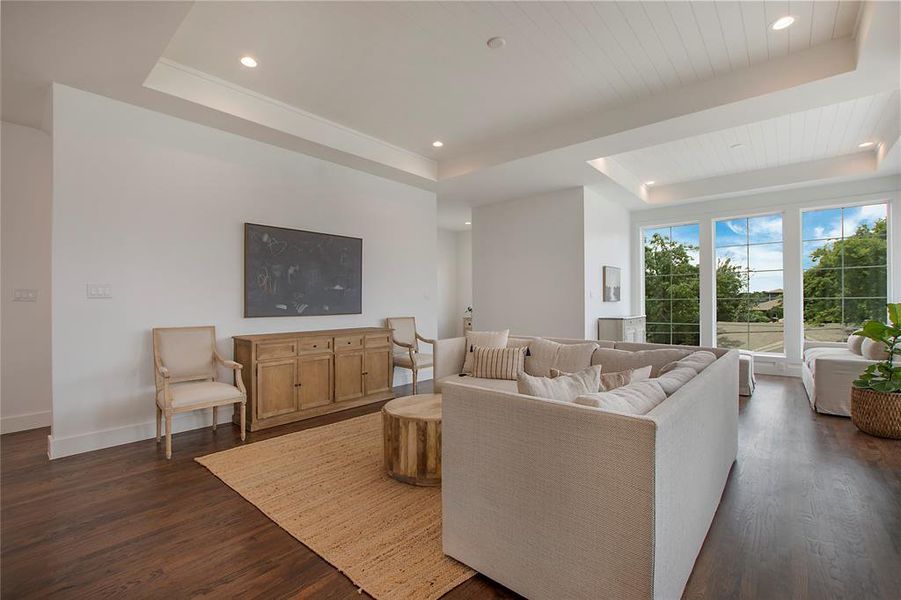 Living room featuring dark hardwood flooring and a tray ceiling