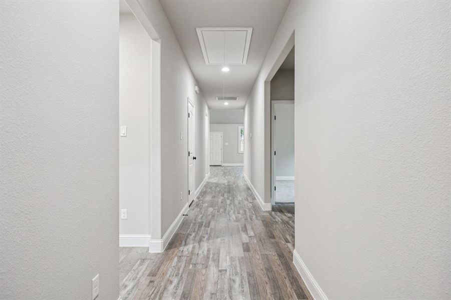 Enter your new home in this spacious hallway featuring attic access, light wood finished floors, and a textured wall. Master bedroom to the right & tow more bedrooms on the left.