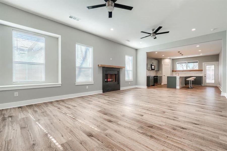 Unfurnished living room with a tile fireplace, ceiling fan, light hardwood / wood-style flooring, and sink