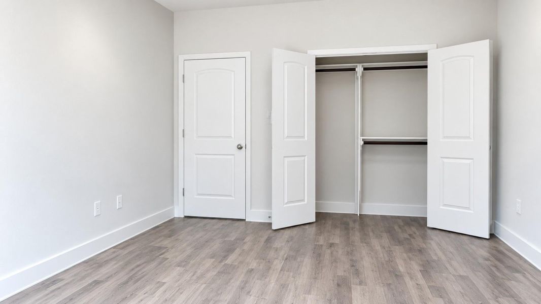 Spacious primary bedroom with elegant flooring and a generous closet featuring double doors for ample storage.