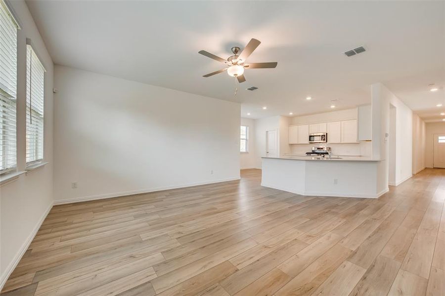 Unfurnished living room featuring ceiling fan and light hardwood / wood-style flooring