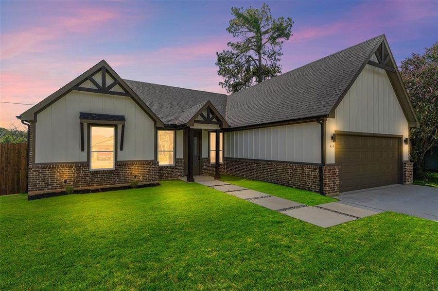Contemporary exterior showcasing a combination of vertical white siding and dark brick, a dark shingle roof, a two-car garage, and a concrete paver walkway