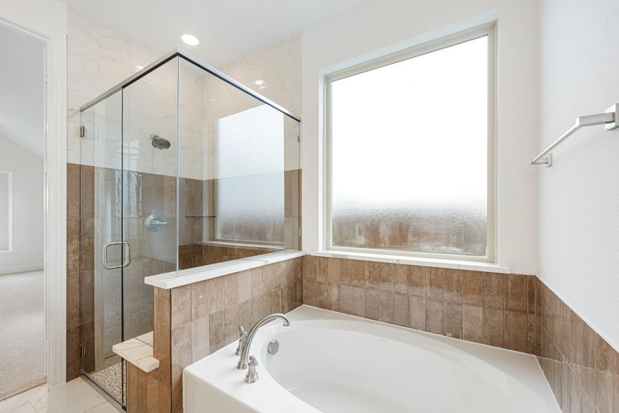 Bathroom with soaking tub, glass-enclosed shower, brown tile surround, and frosted window Bathroom with soaking tub, glass-enclosed shower, brown tile surround, and frosted window
