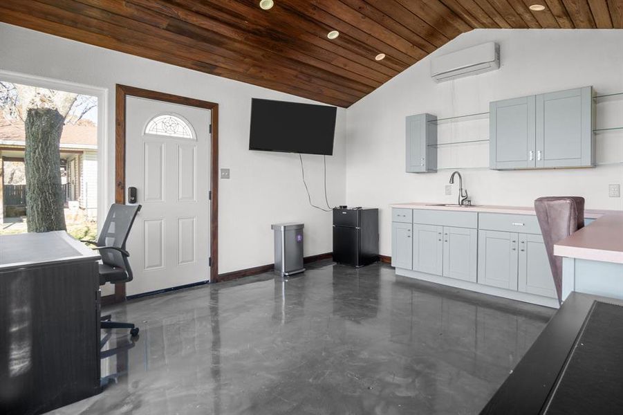 Or flex room, featuring sink, wooden ceiling, black refrigerator, gray cabinets, and a wall mounted AC