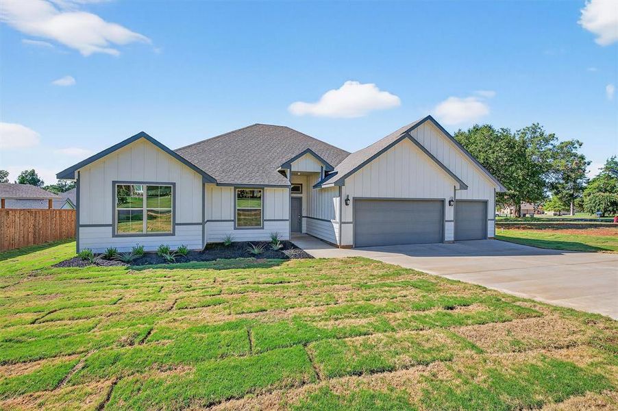 Modern inspired farmhouse with board and batten siding, a shingled roof, concrete driveway, and an attached garage