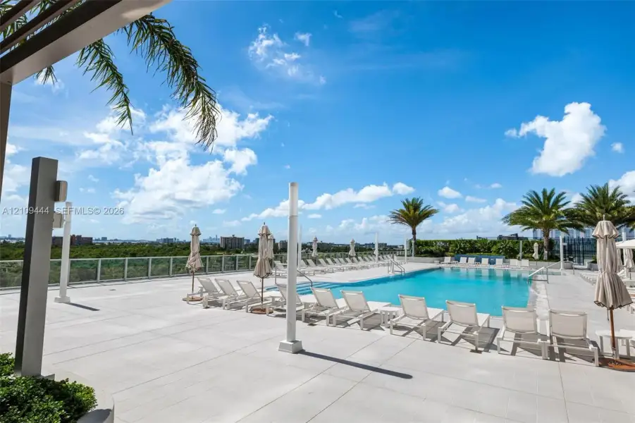 Rooftop swimming pool featuring concrete tile decking, glass perimeter railings, and integrated lighting fixtures