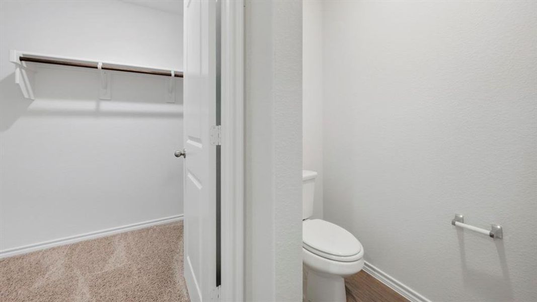 Bathroom featuring a spacious closet and a textured wall
