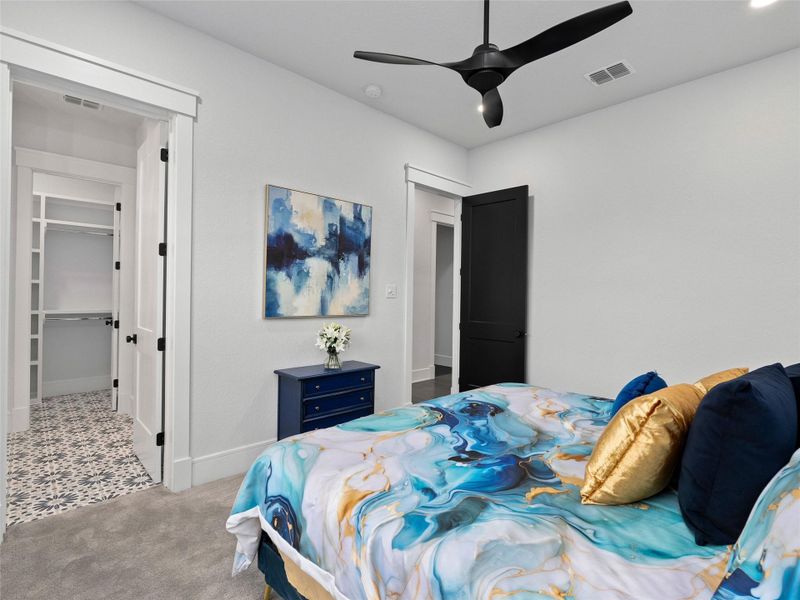 Bedroom with a walk in closet, carpet, and a ceiling fan