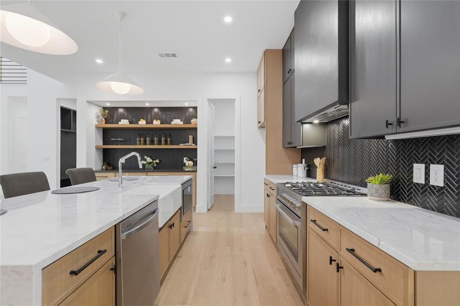 Modern kitchen featuring a large island with white countertops and a farmhouse sink Modern kitchen featuring a large island with white countertops and a farmhouse sink