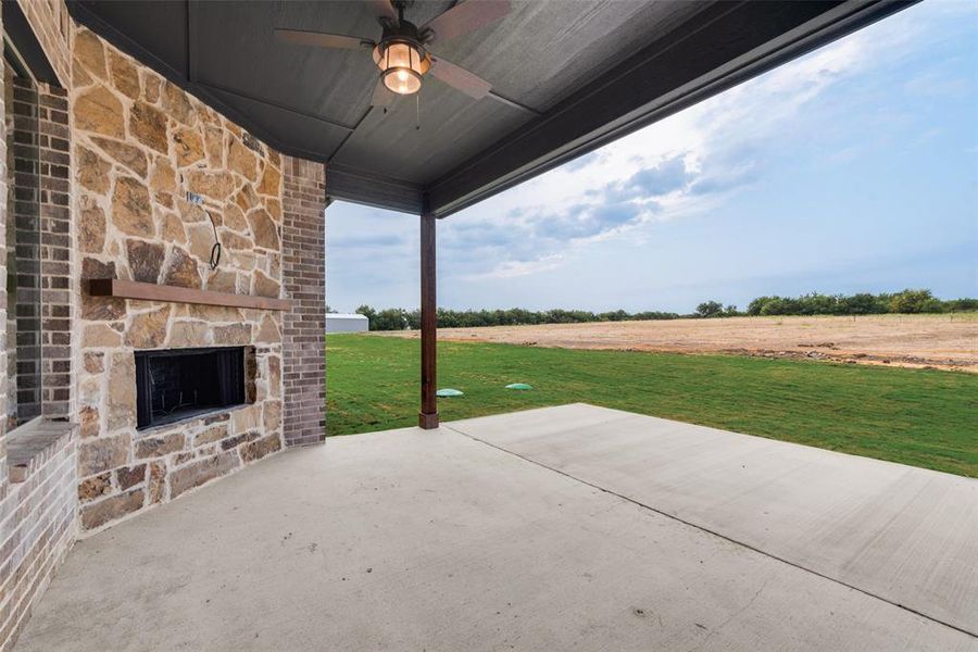 View of patio featuring an outdoor stone fireplace and a ceiling fan View of patio featuring an outdoor stone fireplace and a ceiling fan
