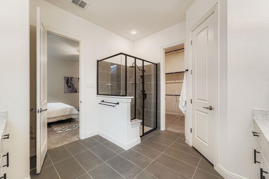 Ensuite bathroom featuring vanity, a spacious closet, a shower stall, and tile patterned flooring Ensuite bathroom featuring vanity, a spacious closet, a shower stall, and tile patterned flooring