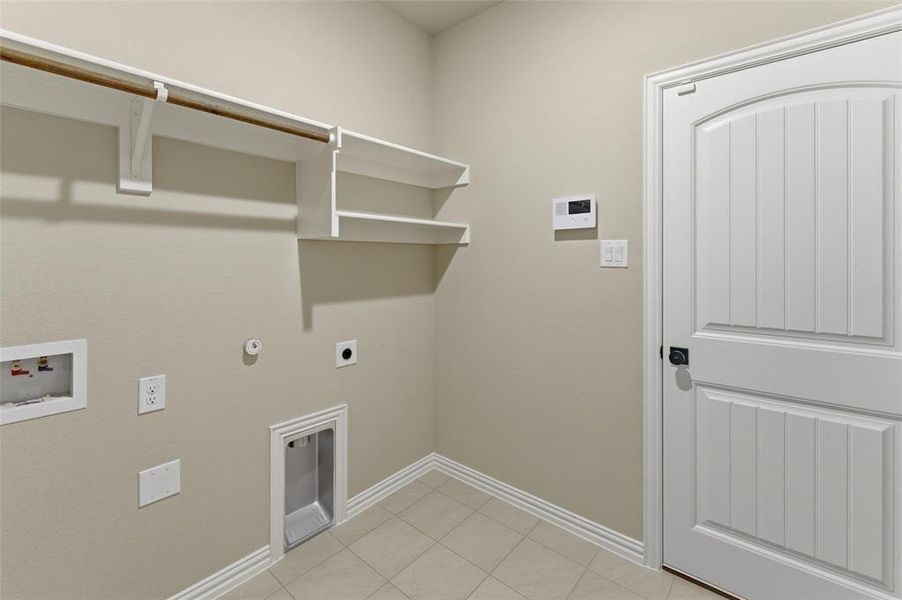 Utility area featuring built-in shelving, a clothing rod, washer/dryer hookups, and neutral wall tones