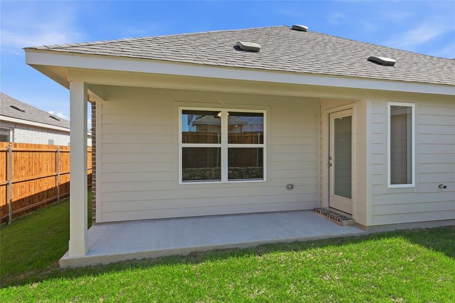 Rear view of property with a patio area, roof with shingles, and a yard