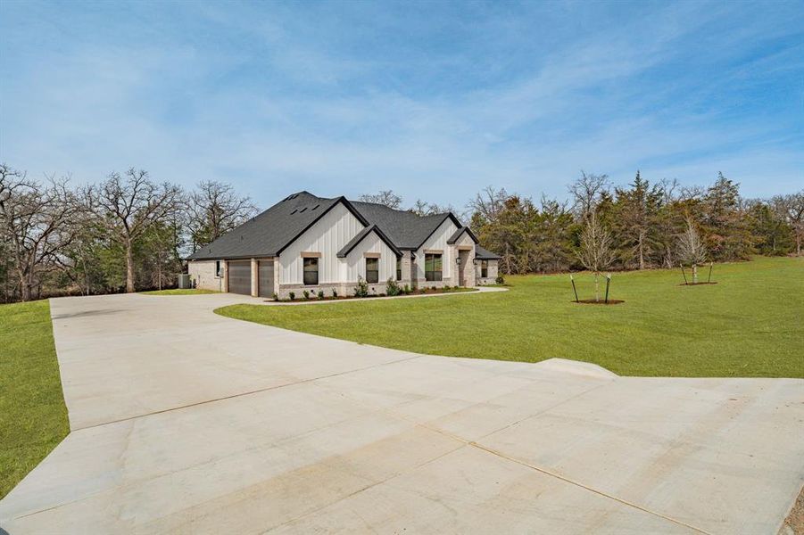 Modern farmhouse style home featuring board and batten siding, a front lawn, driveway, and a garage Modern farmhouse style home featuring board and batten siding, a front lawn, driveway, and a garage