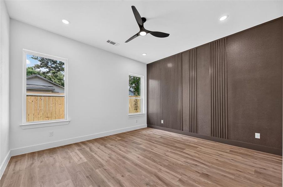 Spacious room featuring wood-finish flooring and a contemporary black ceiling fan Spacious room featuring wood-finish flooring and a contemporary black ceiling fan
