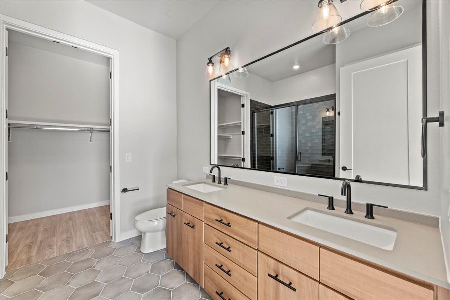 Bathroom featuring a shower with door, vanity, tile patterned floors, and toilet