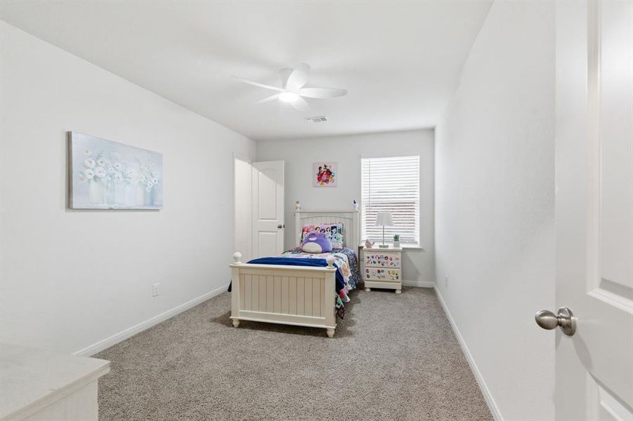 This room features light-colored walls, carpeted flooring, and a ceiling fan