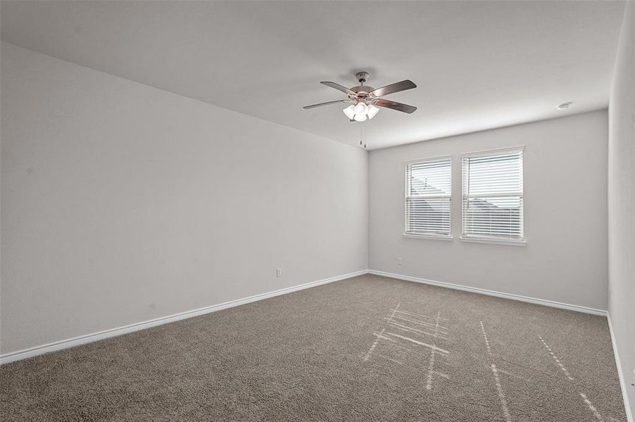 Primary bedroom featuring ceiling fan and carpet