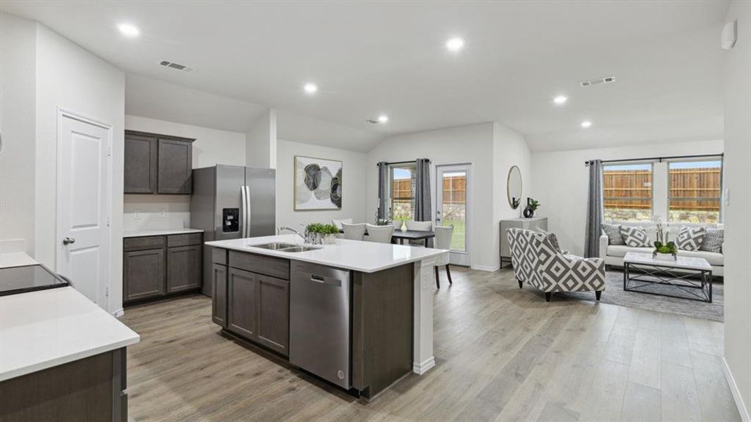 Kitchen with an island with sink, dishwasher, recessed lighting, open floor plan, and dark wood finish cabinetry Kitchen with an island with sink, dishwasher, recessed lighting, open floor plan, and dark wood finish cabinetry