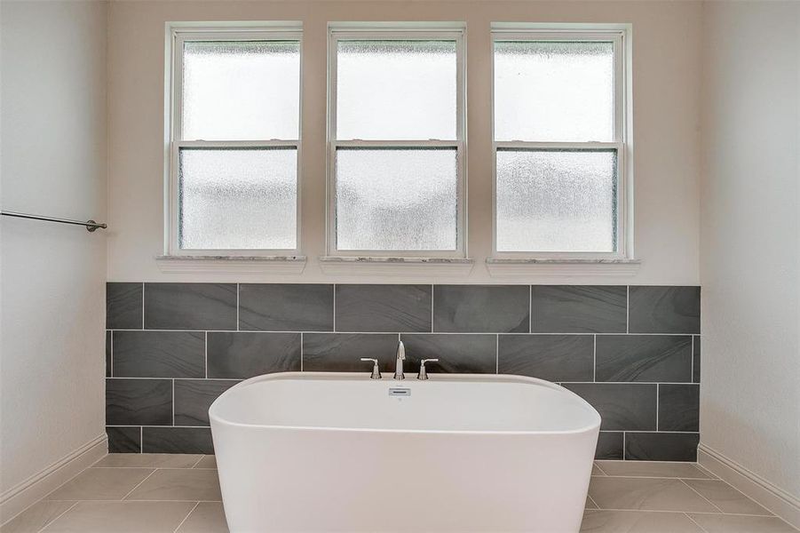 Bathroom featuring tile walls, tile patterned flooring, a healthy amount of sunlight, and a tub