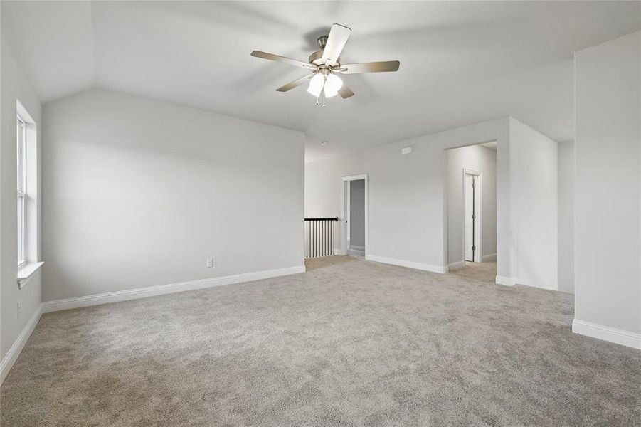 Carpeted spare room featuring a ceiling fan, lofted ceiling, and baseboards