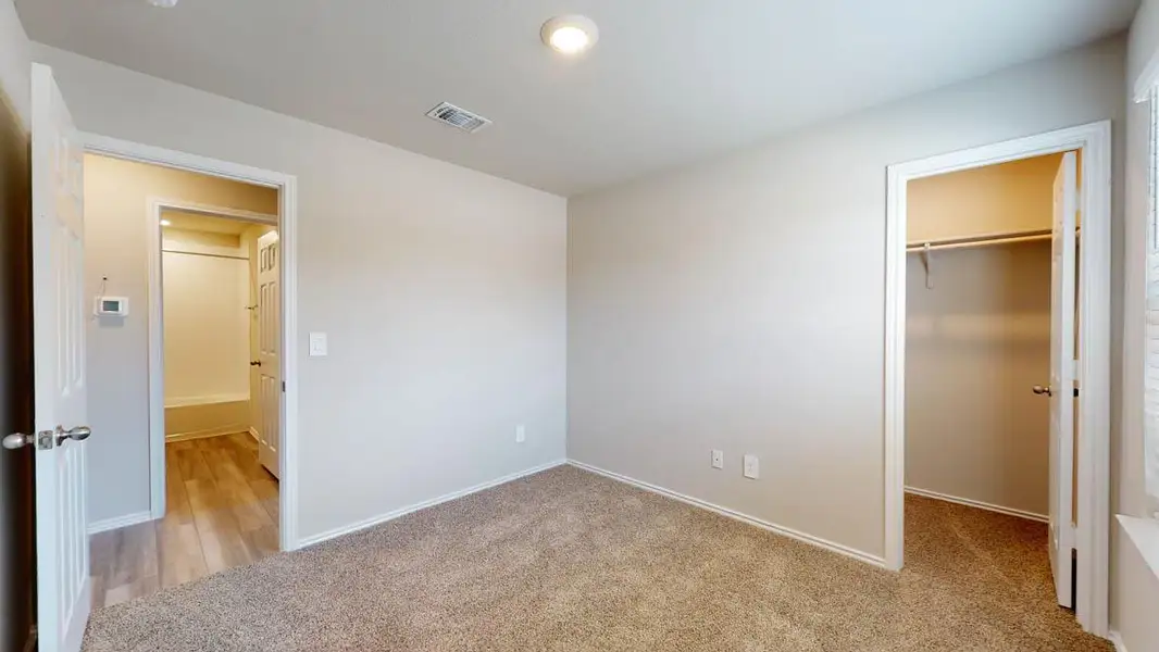 Unfurnished bedroom featuring a spacious closet, light colored carpet, and recessed lighting