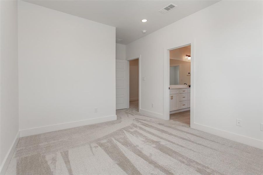 Unfurnished bedroom with light carpet and ensuite bath