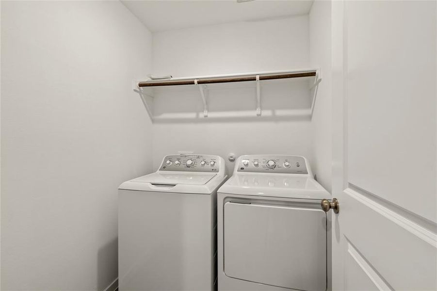 Dedicated laundry space featuring a white top-load washer, a white front-load dryer, and an overhead shelving unit with a hanging rod