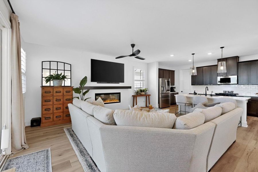 Living area with a glass covered fireplace, a ceiling fan, recessed lighting, and light wood-type flooring