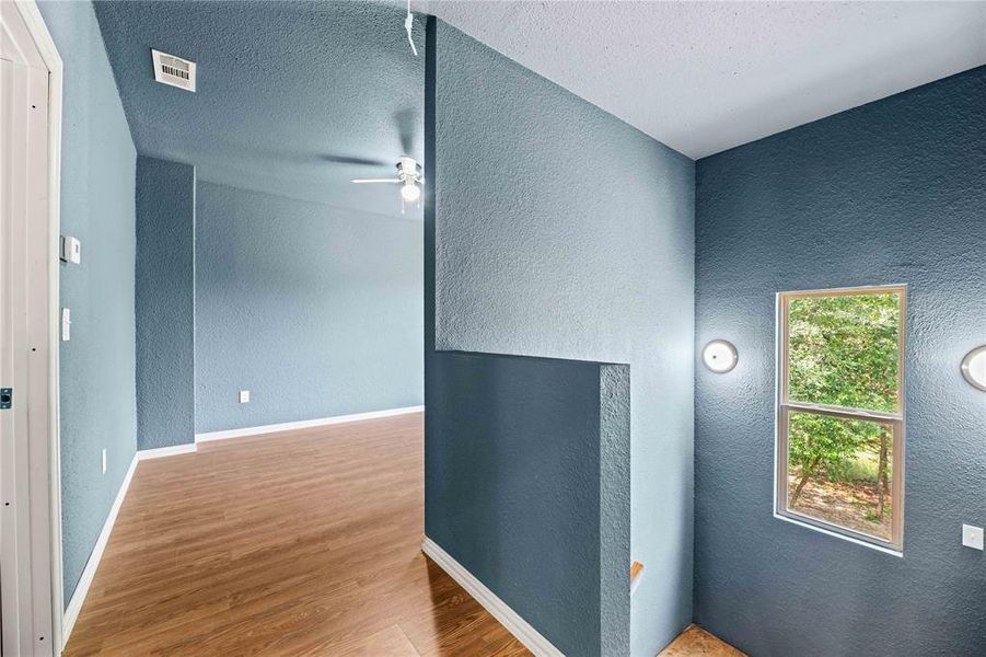 Hallway with a textured ceiling and wood-type flooring Hallway with a textured ceiling and wood-type flooring