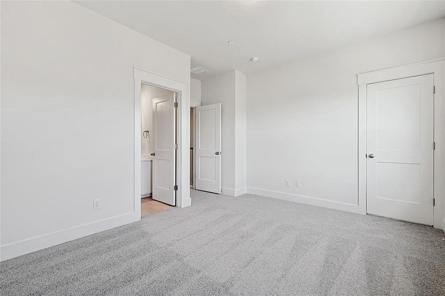 Unfurnished bedroom featuring light carpet and connected bathroom