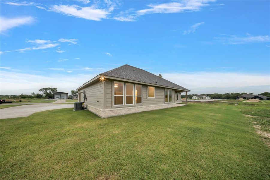 Rear view of property featuring a yard and roof with shingles Rear view of property featuring a yard and roof with shingles