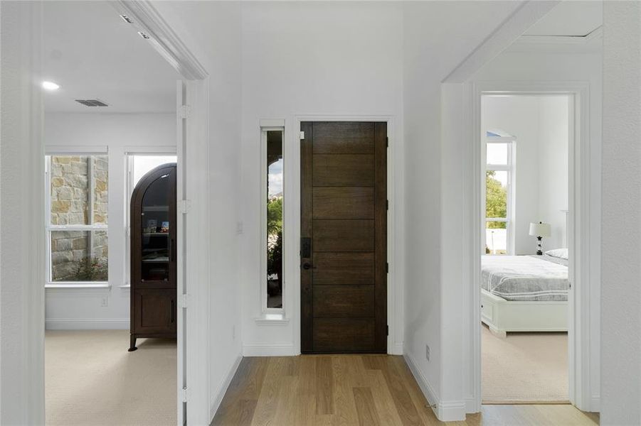 Entryway featuring a solid wood-finish door with sidelight, light wood-finish flooring, and white walls