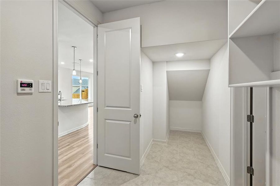 Hallway featuring light tile patterned flooring and baseboards Hallway featuring light tile patterned flooring and baseboards