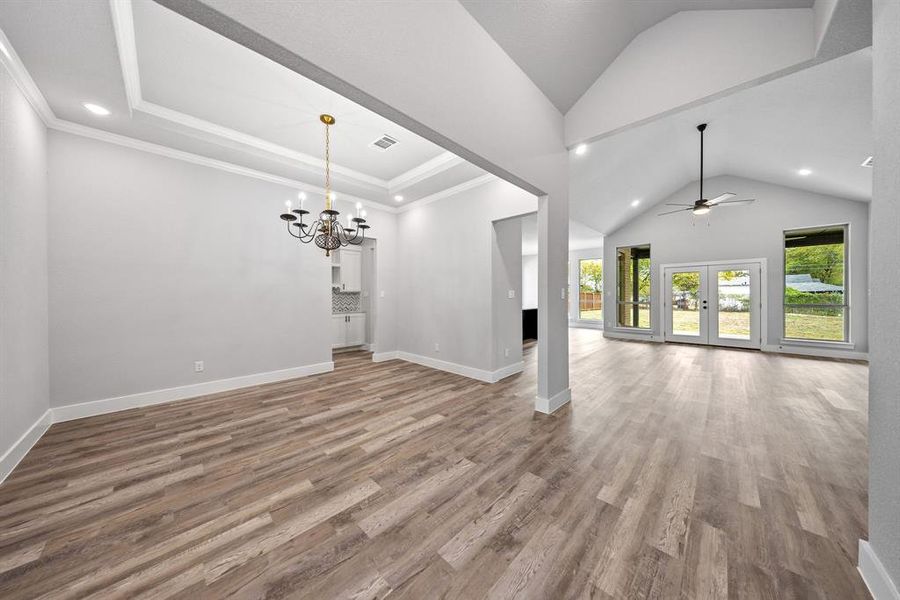 Unfurnished living room with a ceiling fan, light wood-style flooring, a chandelier, recessed lighting, and french doors