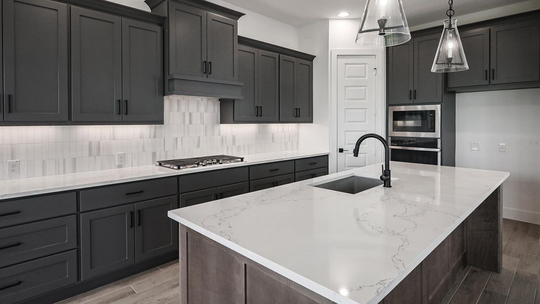 Kitchen featuring appliances with stainless steel finishes, wood finished floors, light stone counters, tasteful backsplash, and recessed lighting Kitchen featuring appliances with stainless steel finishes, wood finished floors, light stone counters, tasteful backsplash, and recessed lighting