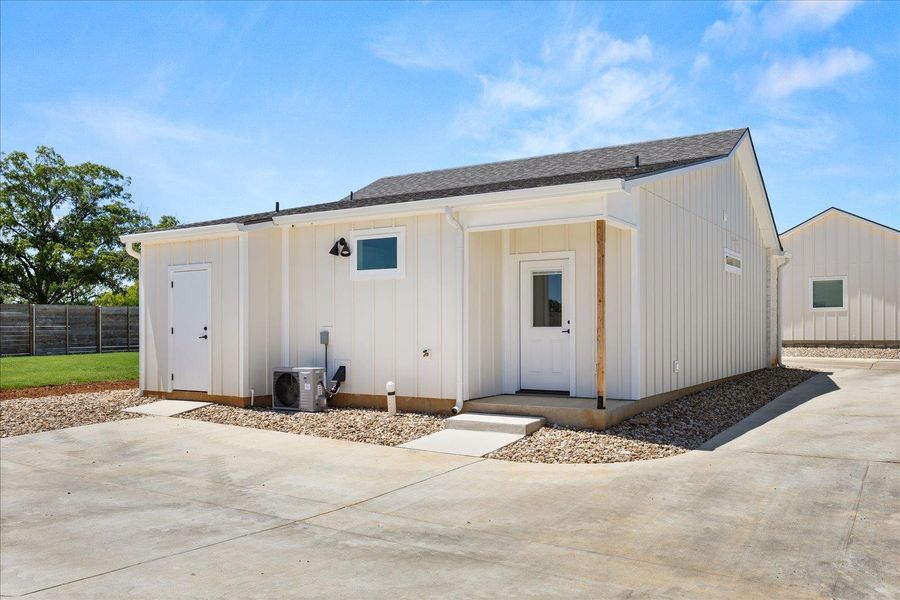 White board and batten siding graces this charming exterior, set against a concrete driveway and lush green lawn.