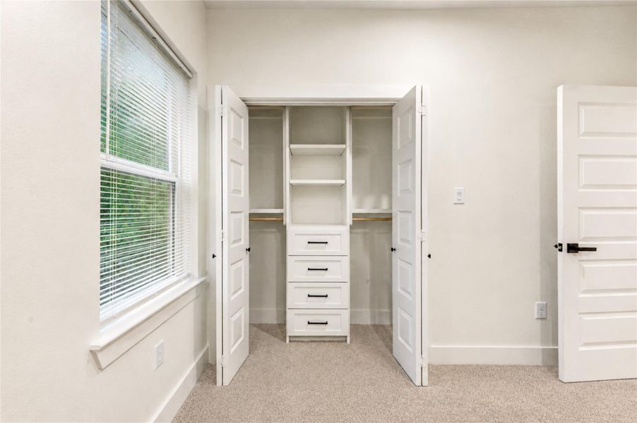 Bright and airy closet space for the 4th bedroom, with built-in shelving and drawers, complemented by natural light from a nearby window.