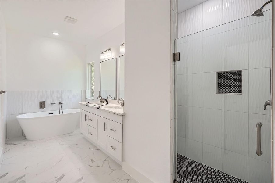 Bathroom featuring a shower stall, double vanity, a soaking tub