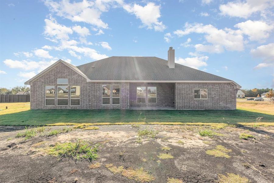 Rear view of property with a yard, brick siding, and a chimney