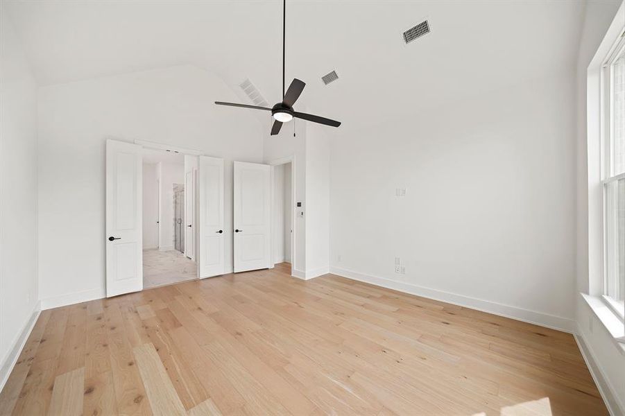 Unfurnished bedroom with light wood-style flooring, a ceiling fan, and high vaulted ceiling Unfurnished bedroom with light wood-style flooring, a ceiling fan, and high vaulted ceiling