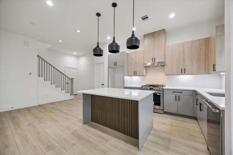 Designer kitchen with statement island, pendant lighting, and sleek finishes Designer kitchen with statement island, pendant lighting, and sleek finishes
