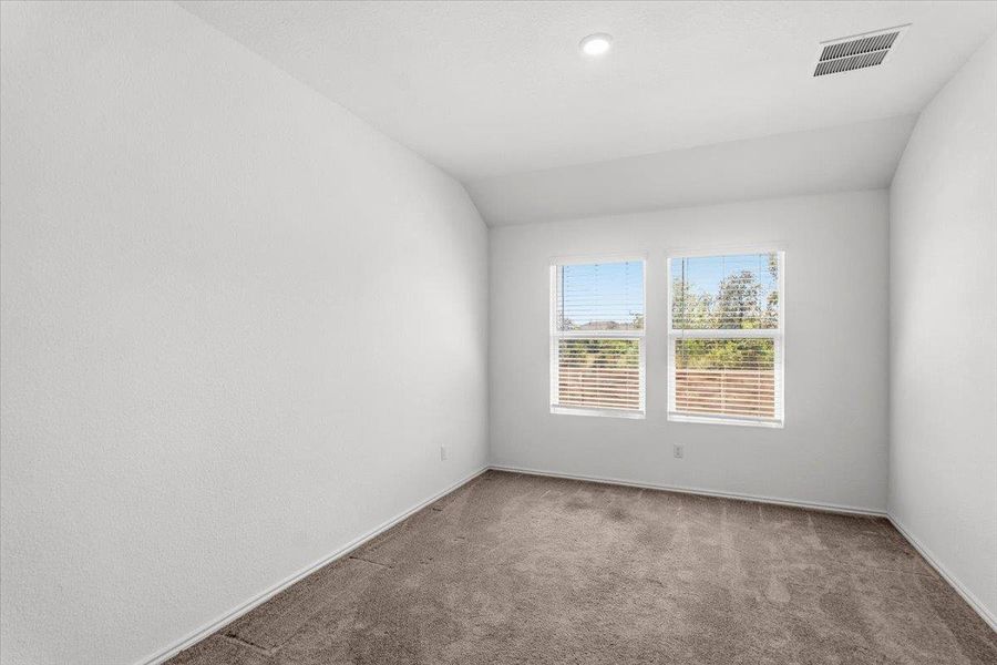 Carpeted empty room featuring vaulted ceiling and baseboards