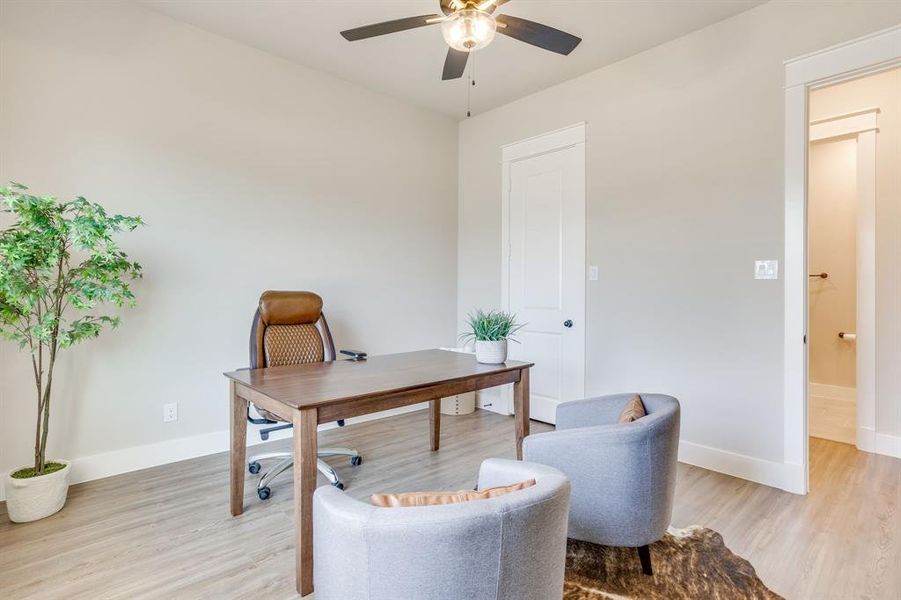 Bedroom 3 featuring light wood-finish flooring, light gray walls, a white paneled door, and a ceiling fan with integrated lighting