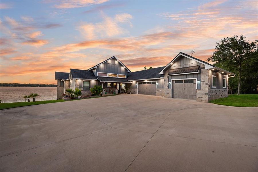 View of front of home with board and batten siding, driveway, an attached garage, and stone siding View of front of home with board and batten siding, driveway, an attached garage, and stone siding