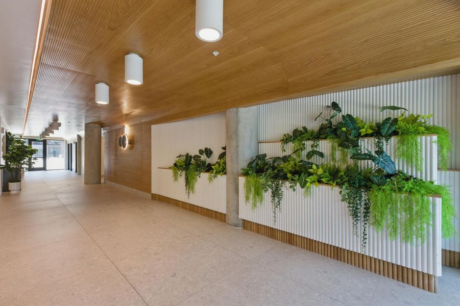 An inviting foyer showcases textured wood paneling, contemporary lighting, and lush built-in planters.