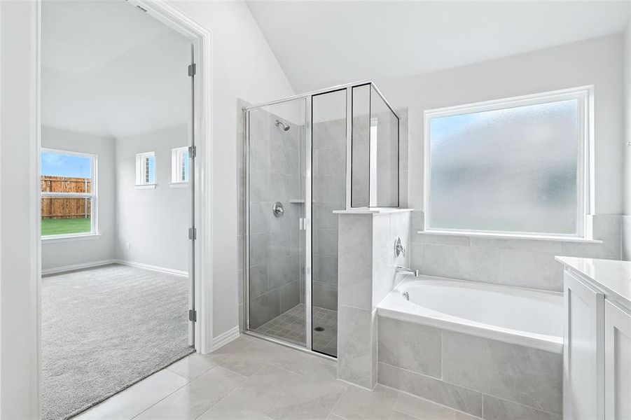 Bathroom featuring a shower stall, a bath, tile patterned floors, vanity, and lofted ceiling